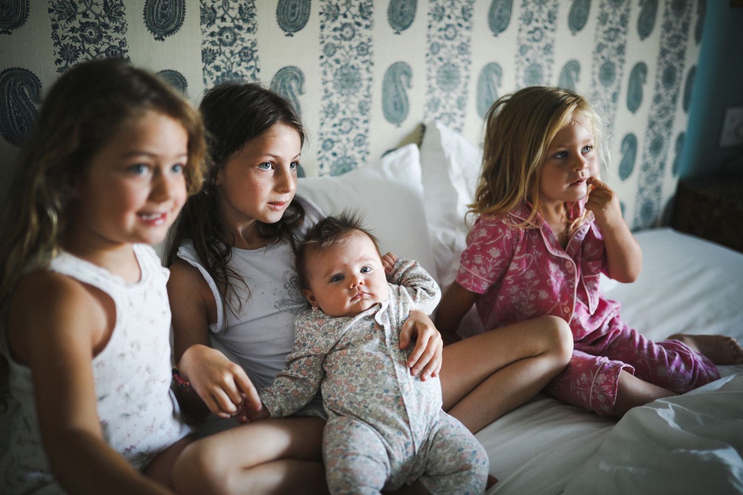 Siblings sitting together on bed with baby, in-home family photography Sydney