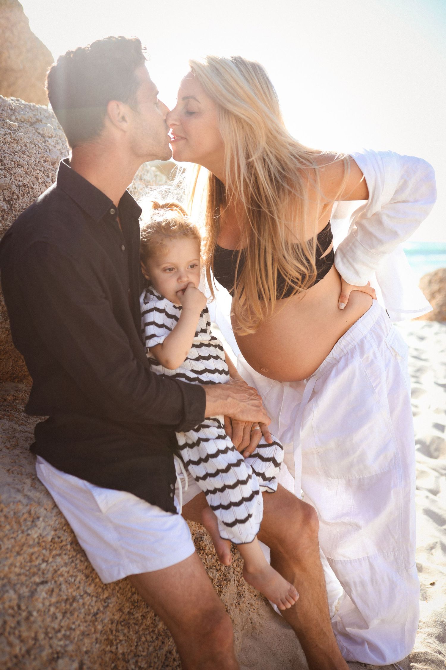 Family embracing on the beach with pregnant mother, father and toddler, Sydney maternity and family photography