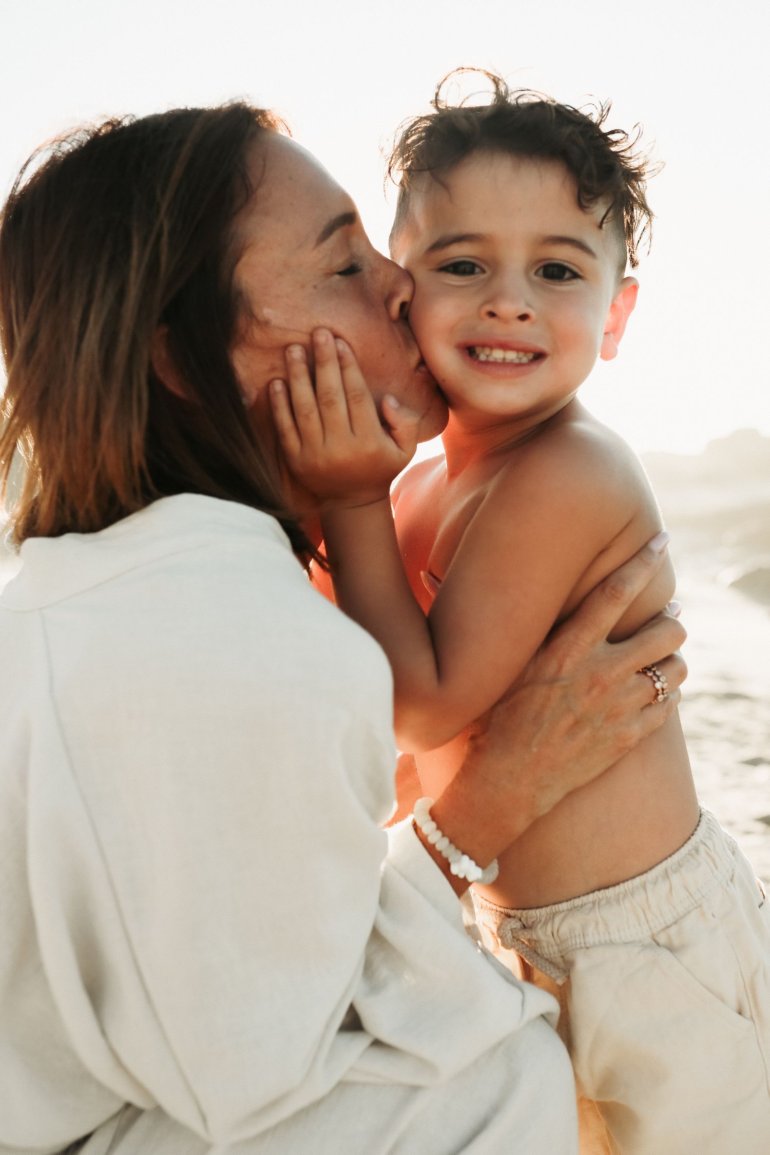 Mother kissing son's cheek in golden sunlight, Sydney family photography session