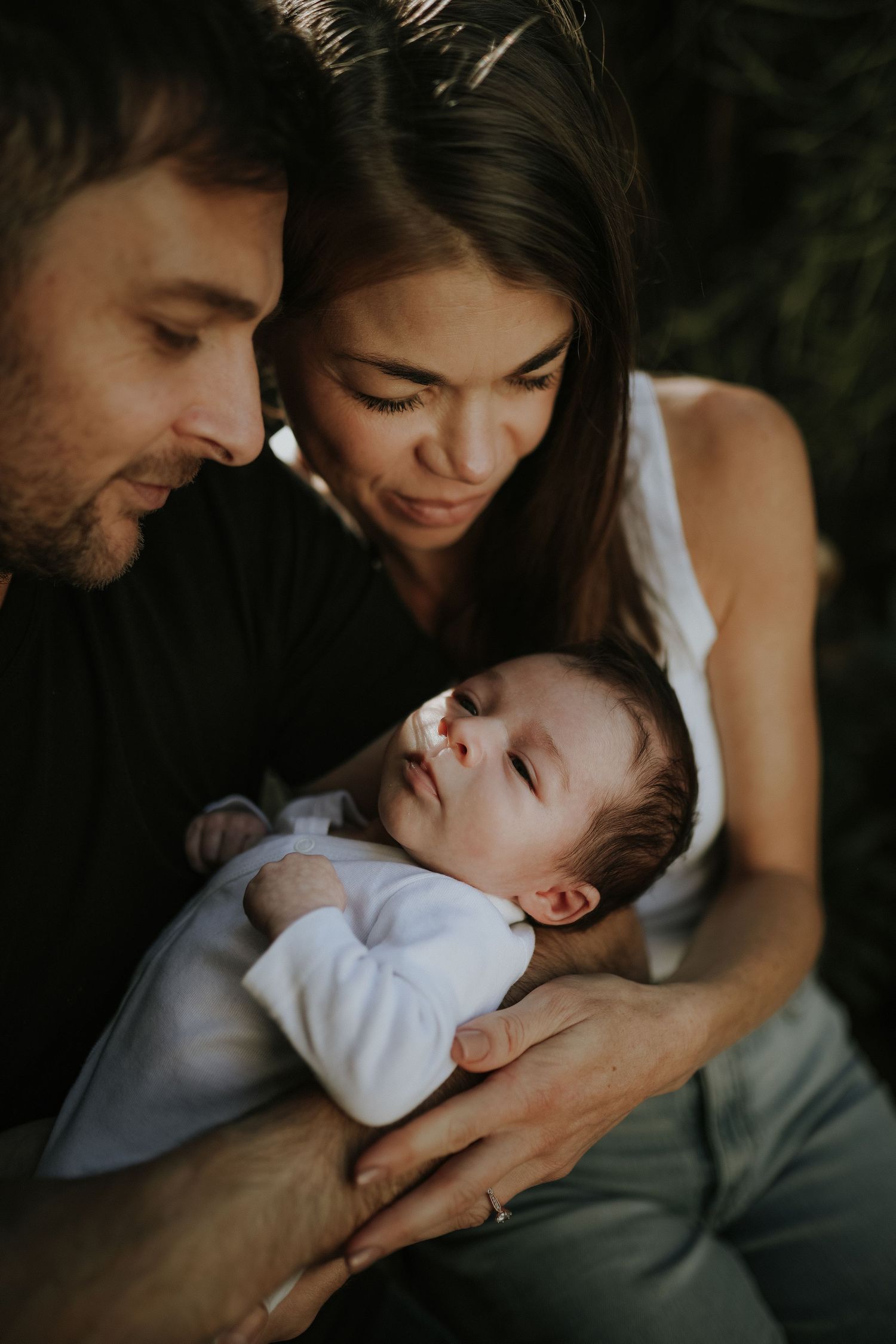 Parents looking down at newborn baby together outdoors, Sydney newborn photography