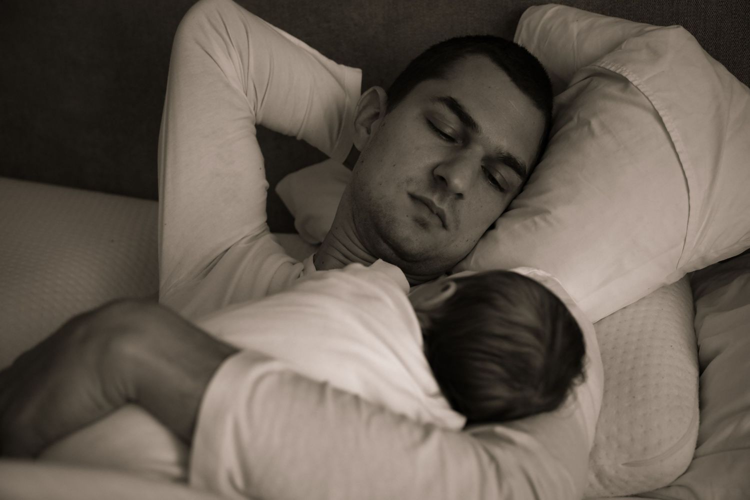 Father sleeping with newborn baby on chest, in-home newborn photography Sydney