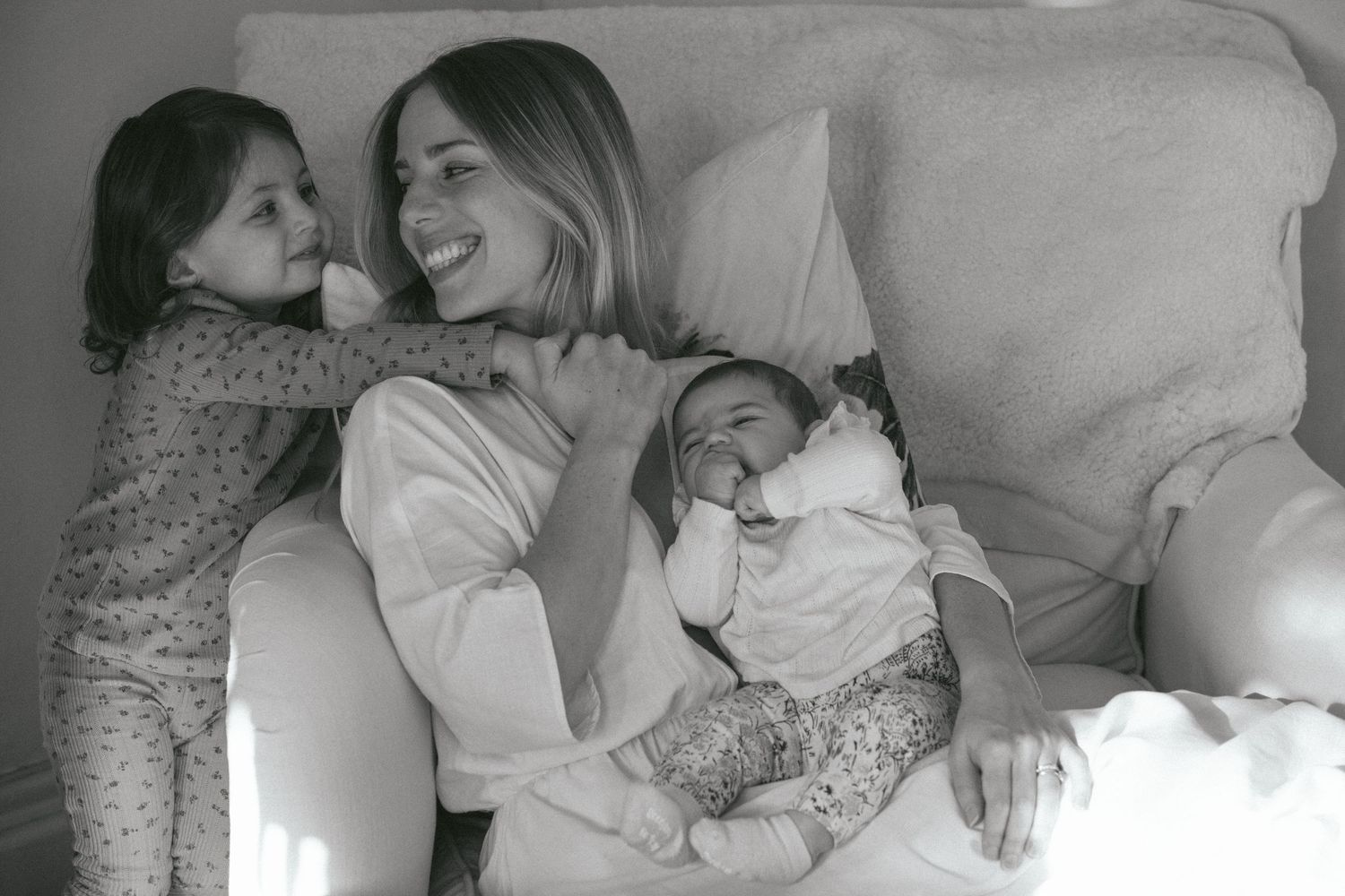Black and white portrait of mother with toddler and newborn baby in bed, in-home newborn photography Sydney