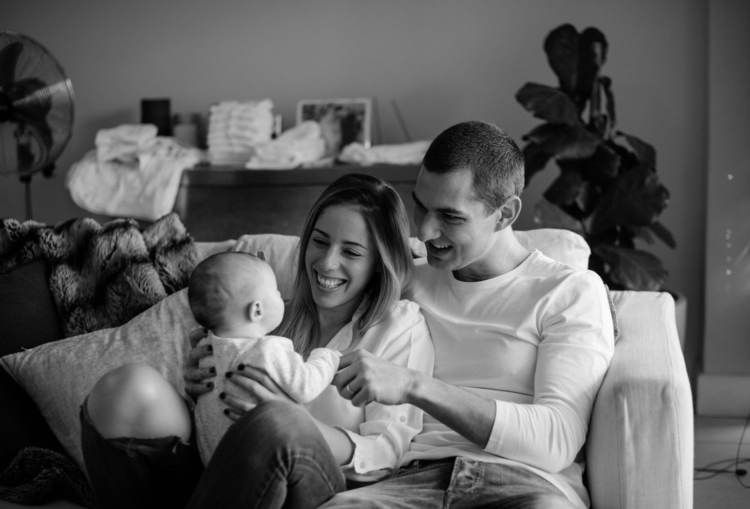 Black and white portrait of parents with newborn baby on couch, in-home newborn photography Sydney