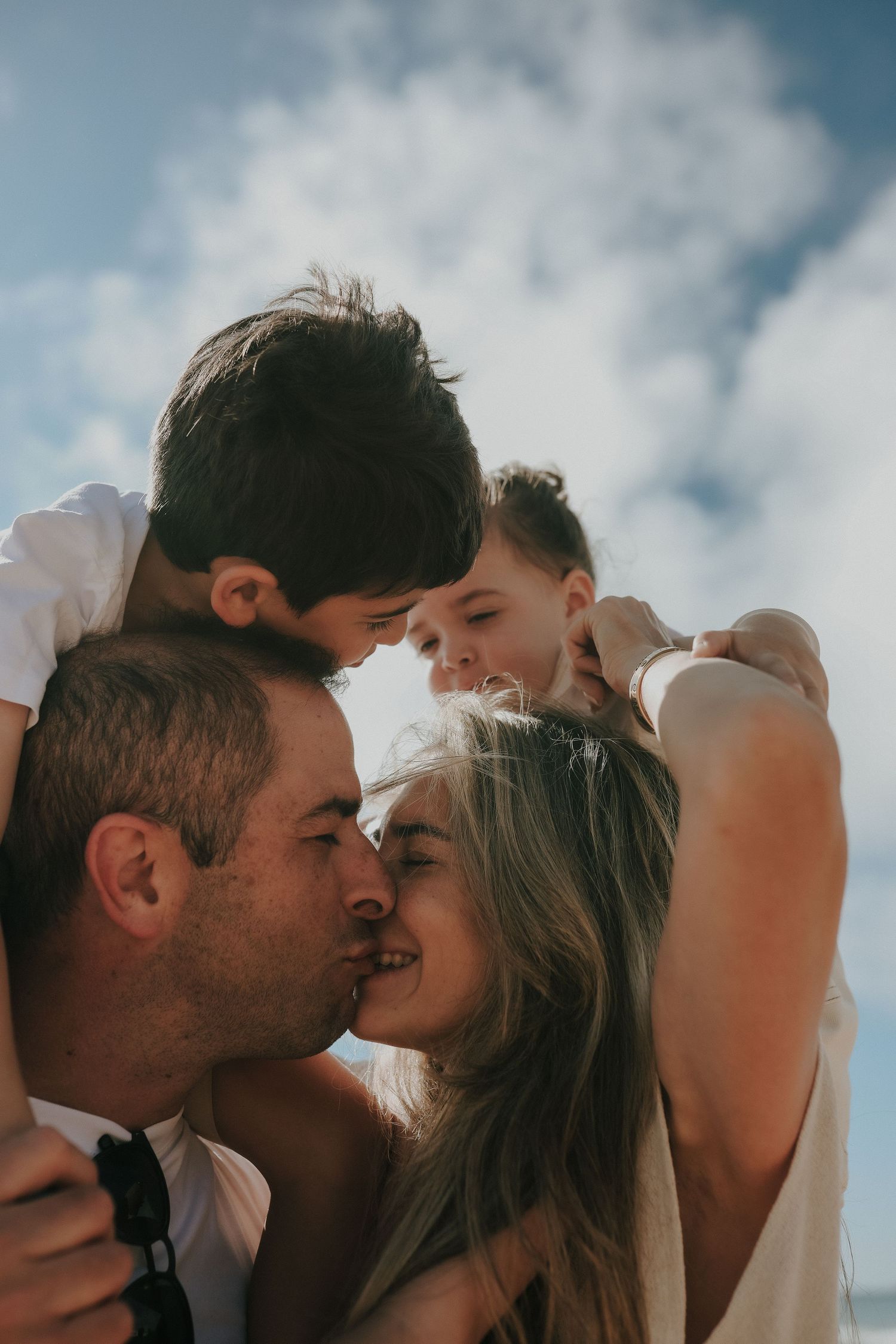 Family embracing outdoors with cloudy sky backdrop, Sydney family photography session