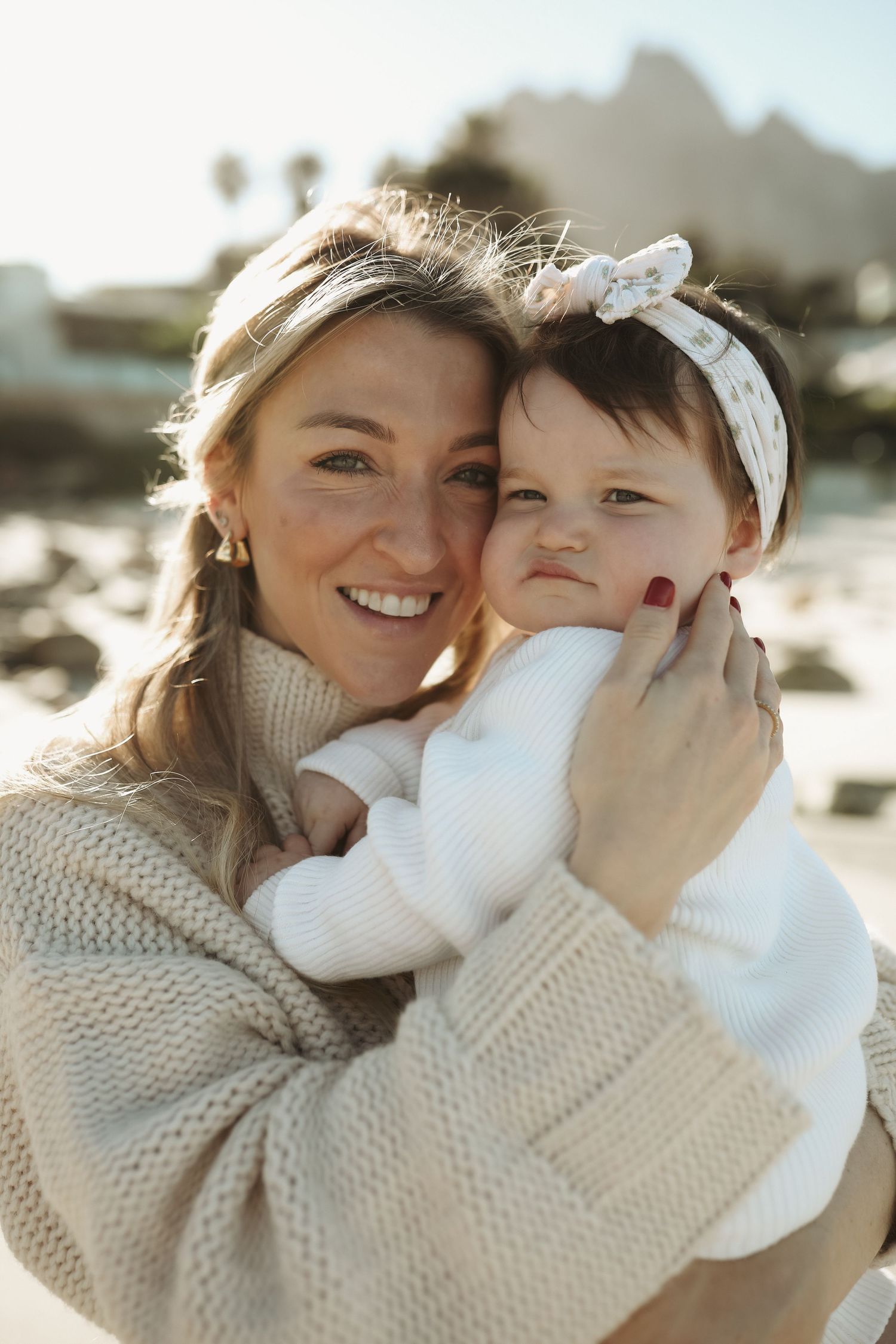 Mother holding smiling toddler daughter with coastal backdrop, Sydney family photography