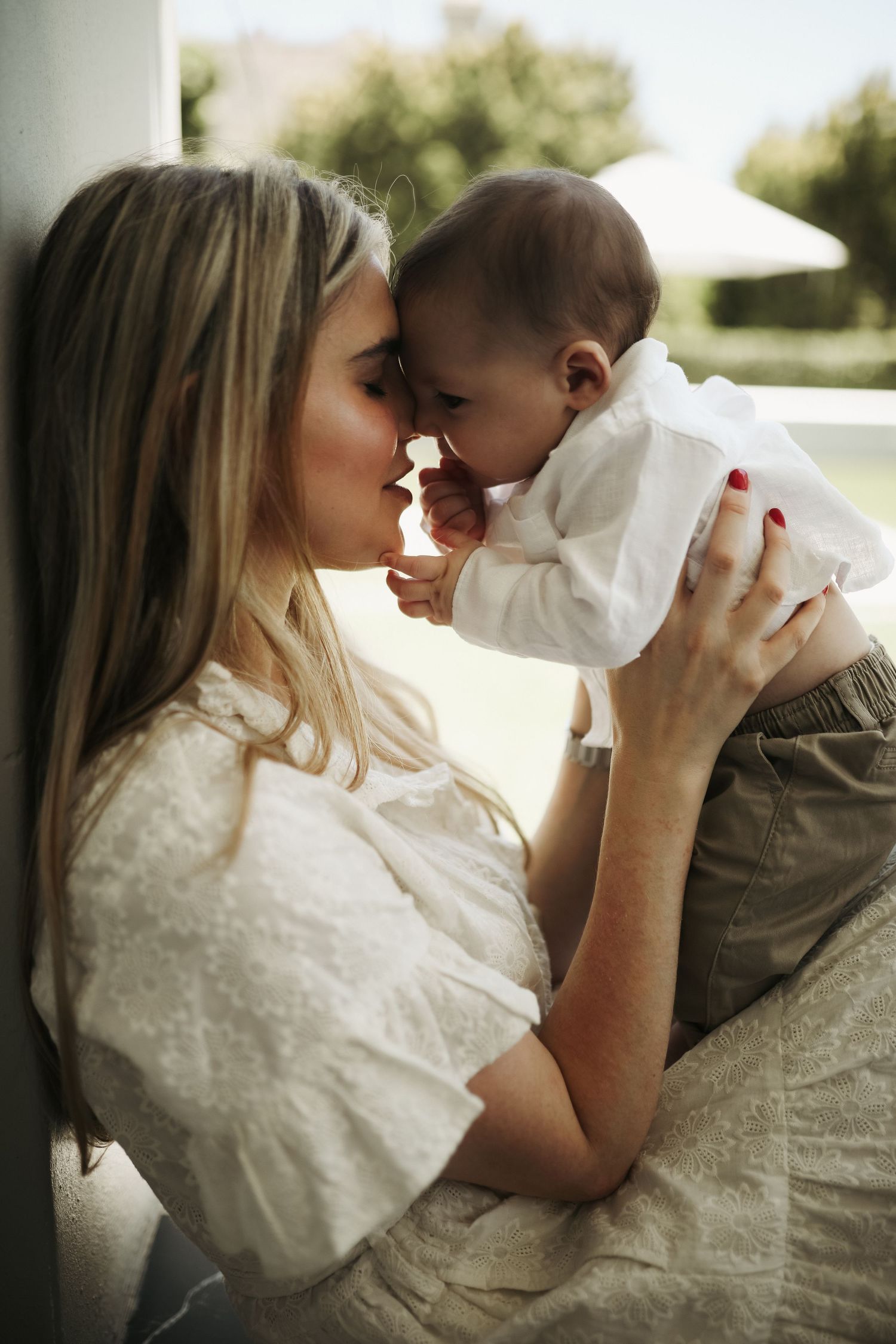 Mother lifting baby for nose-to-nose moment in natural window light, Sydney family photographer