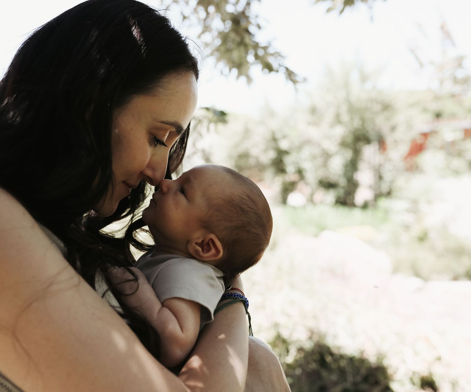 Mother kissing newborn baby's nose in garden light, Sydney newborn photography