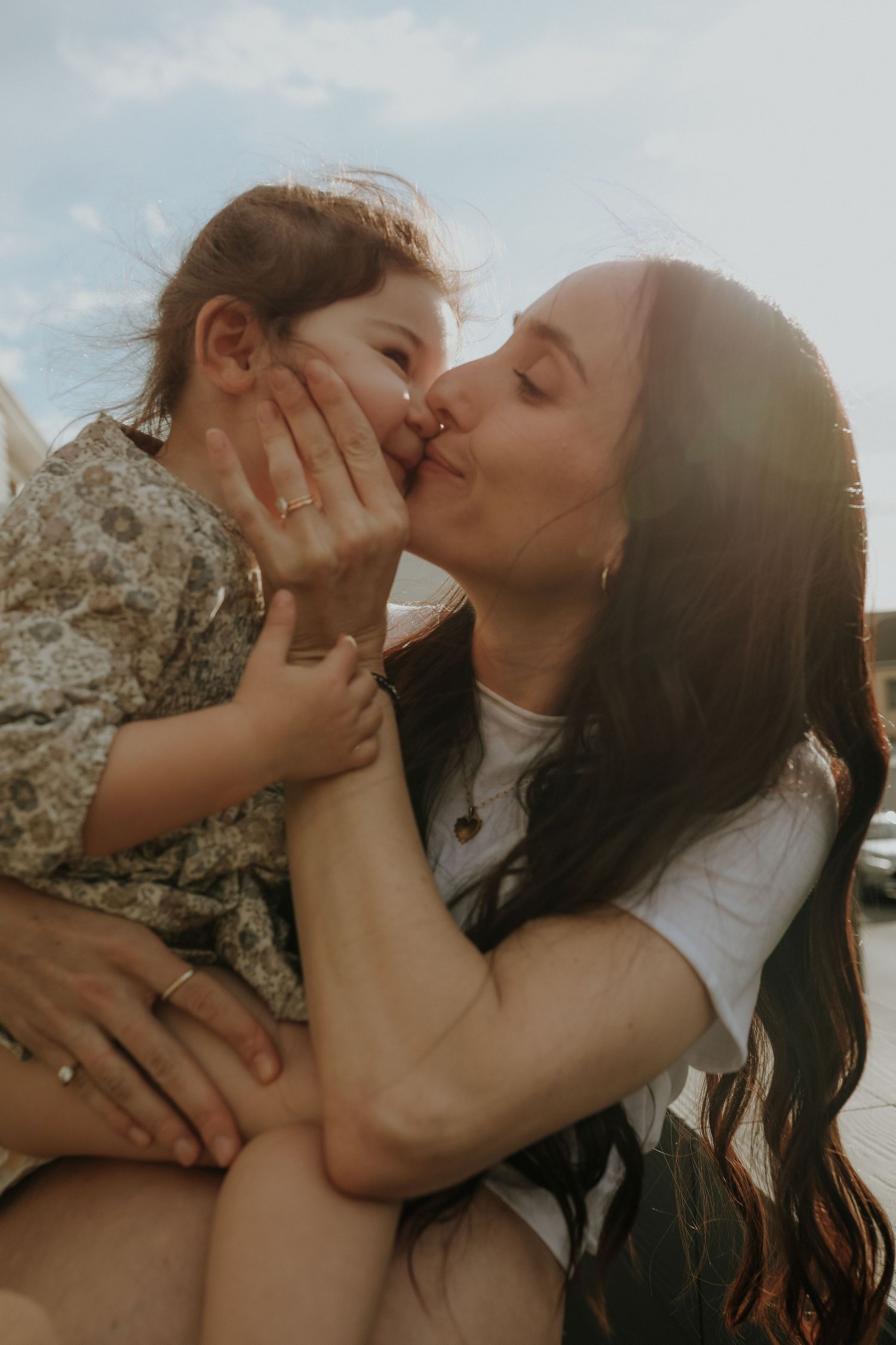 Mother kissing daughter's cheek in golden sunlight, Sydney family photography session