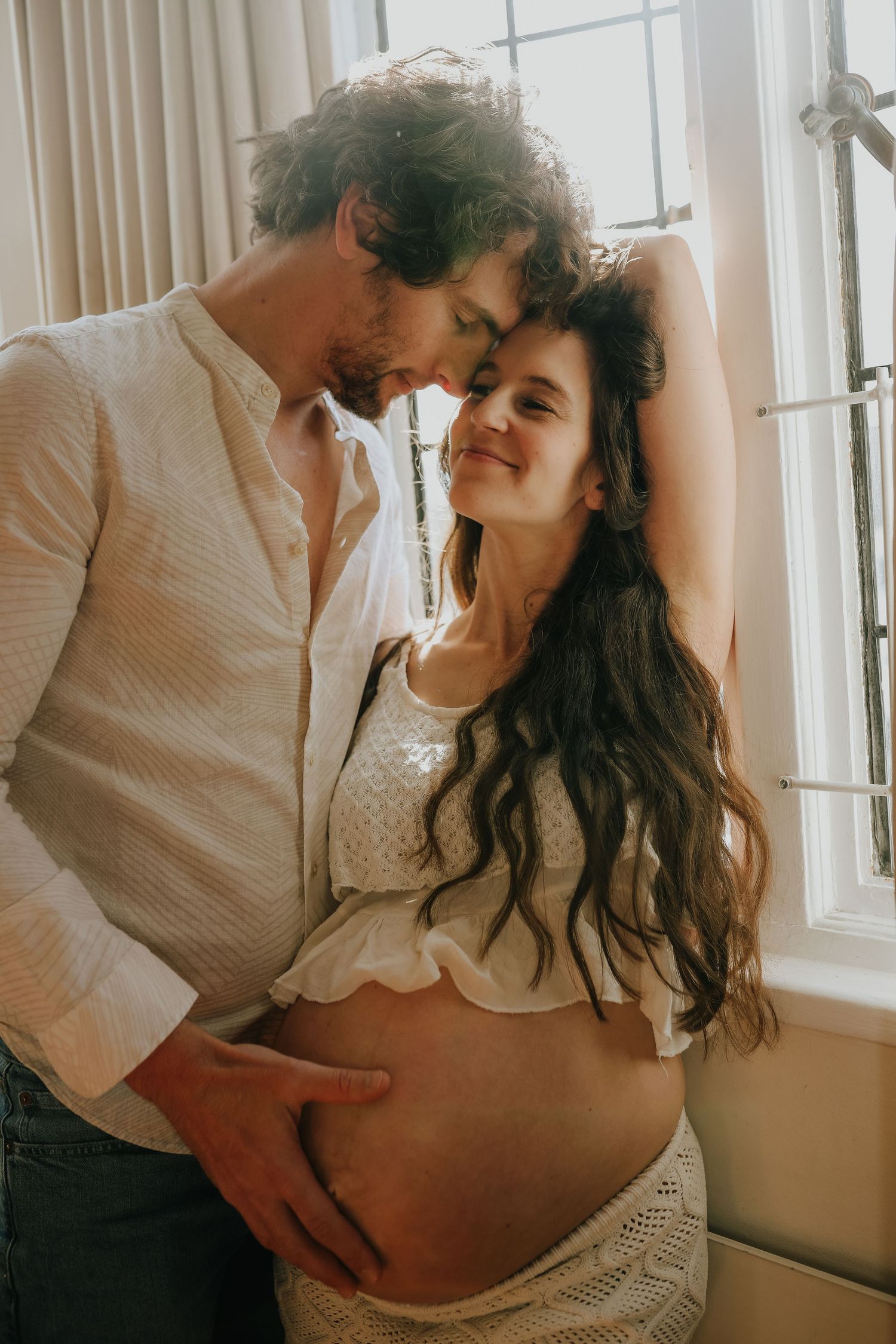 Pregnant couple embracing in natural window light, Sydney maternity photography