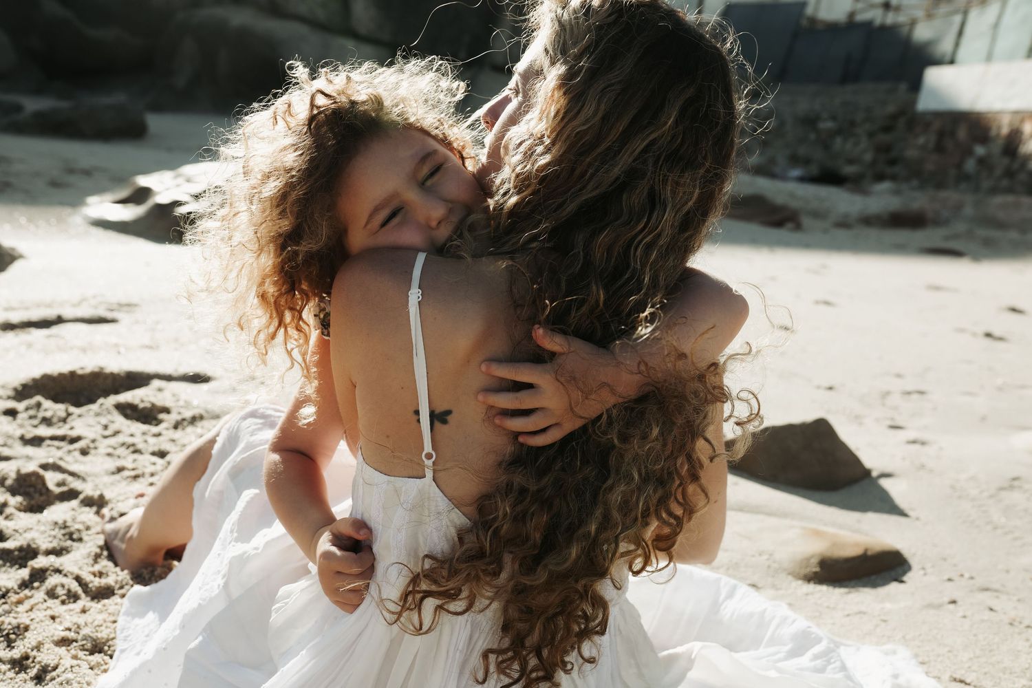Mother and daughter embracing on the beach, Sydney family photography session
