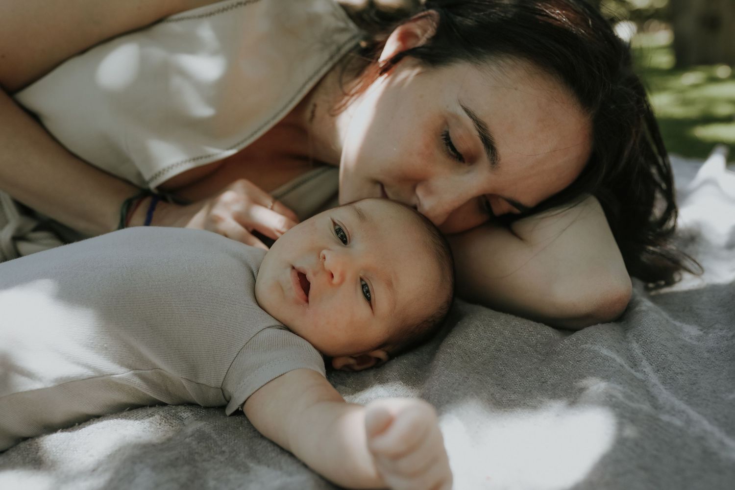 Mother lying with baby in dappled outdoor light, Sydney family photography