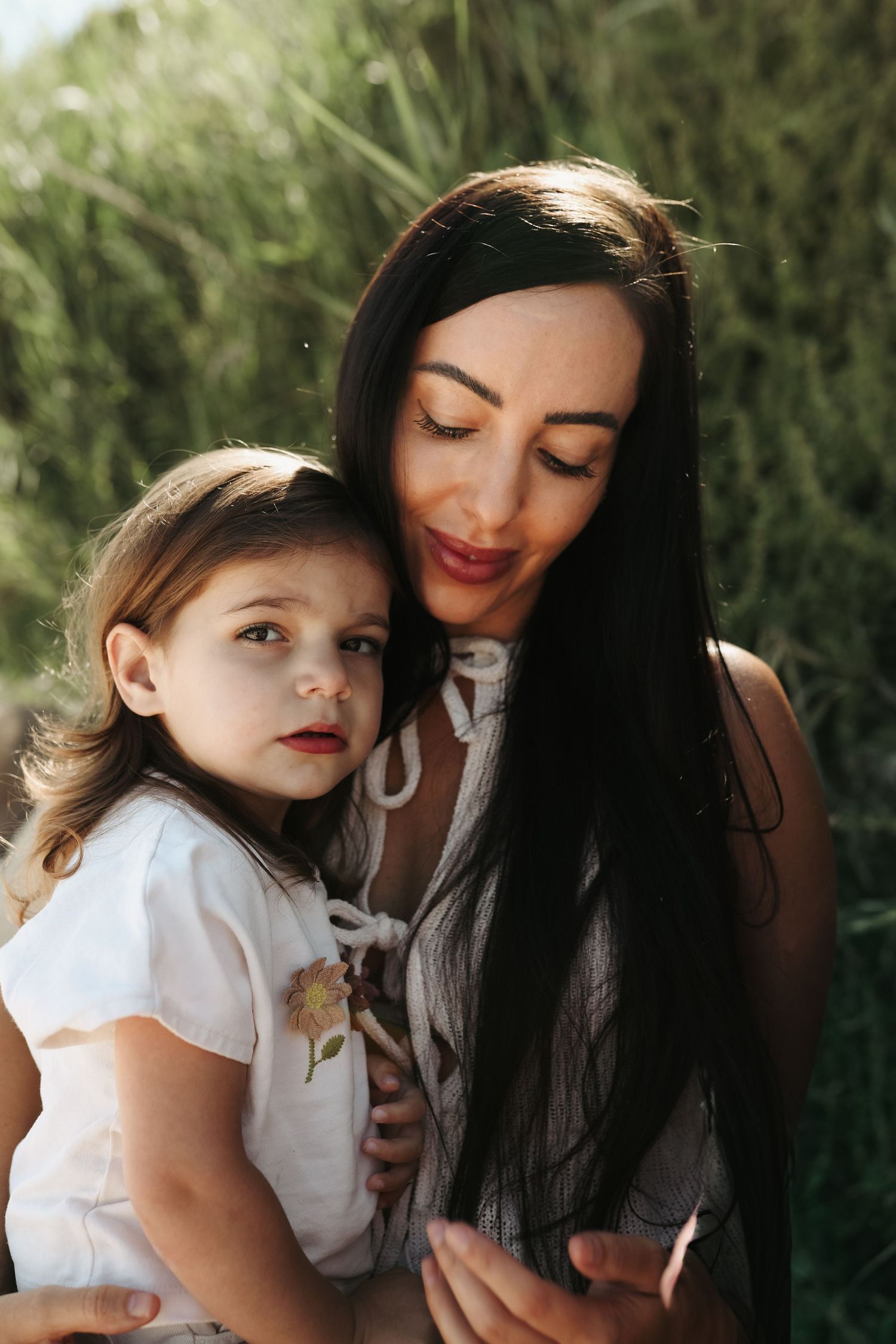 Mother smiling gently down at young daughter in garden setting, Sydney family photography