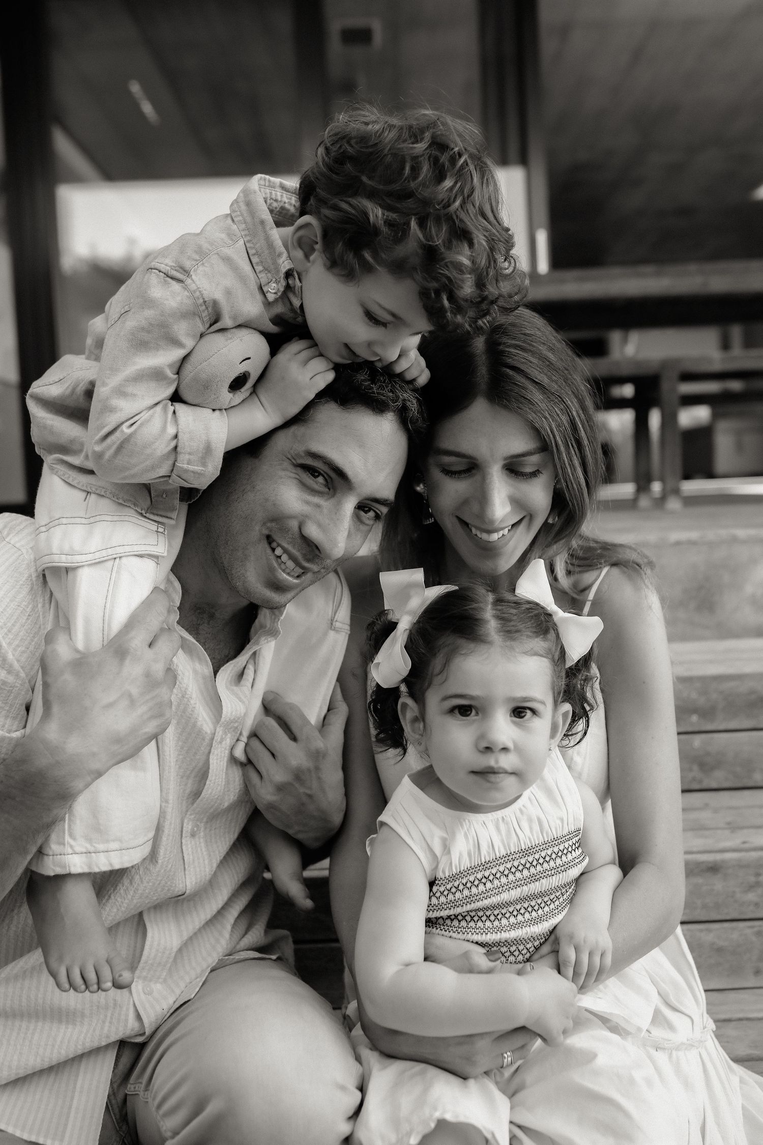 Black and white portrait of mother and father embracing two children outdoors, Sydney family photography