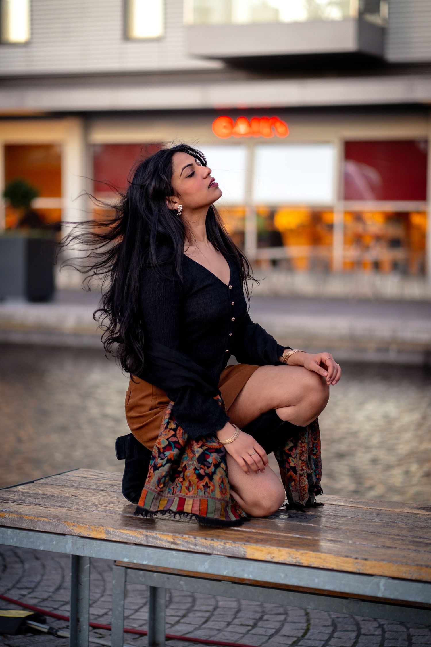 Fashion portrait of a woman in a patterned skirt kneeling on a table at dusk, by Anya MacLaren Photography
