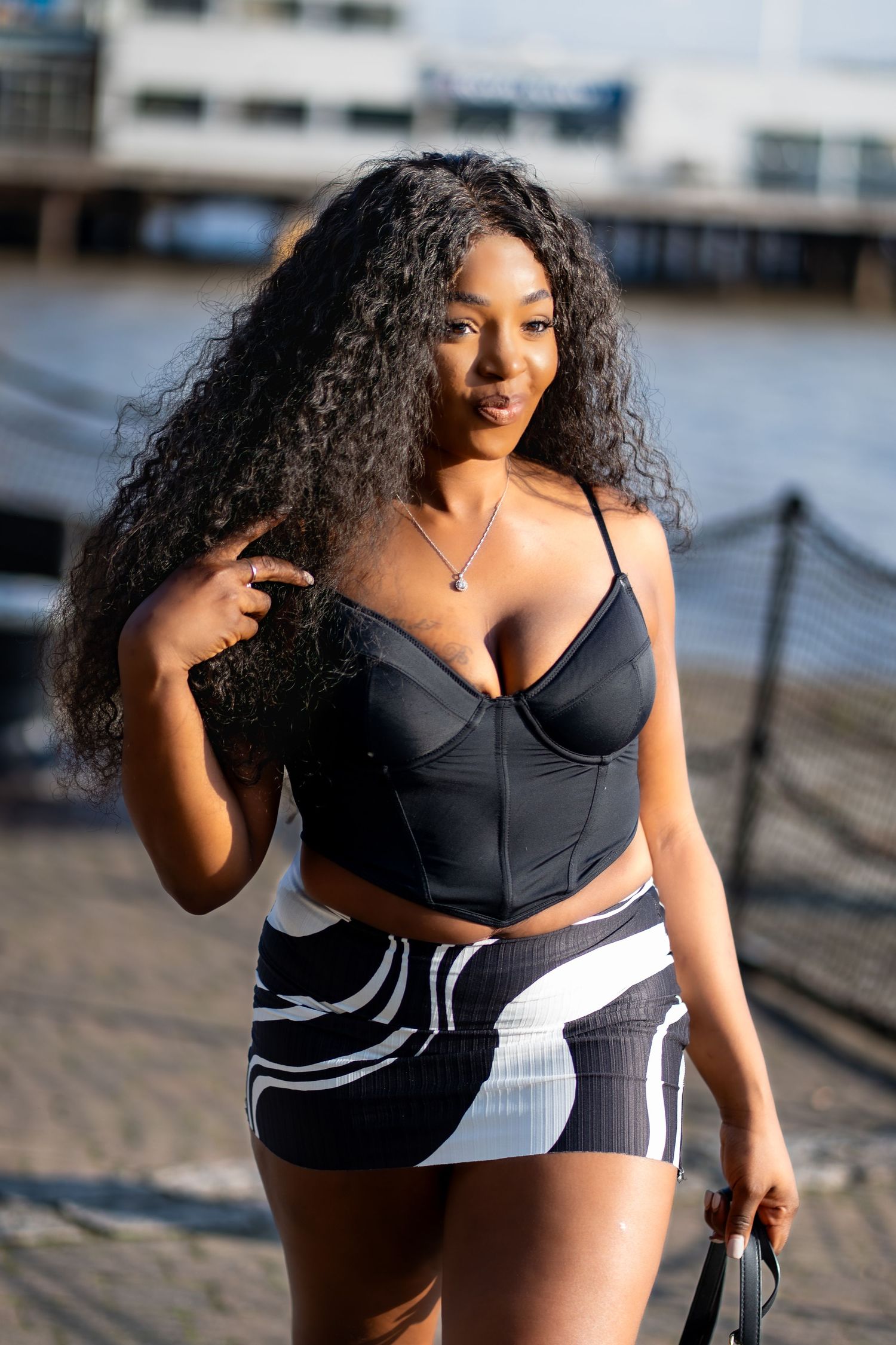 Fashion portrait of a woman in a black corset top and printed skirt by the Thames, by Anya MacLaren Photography