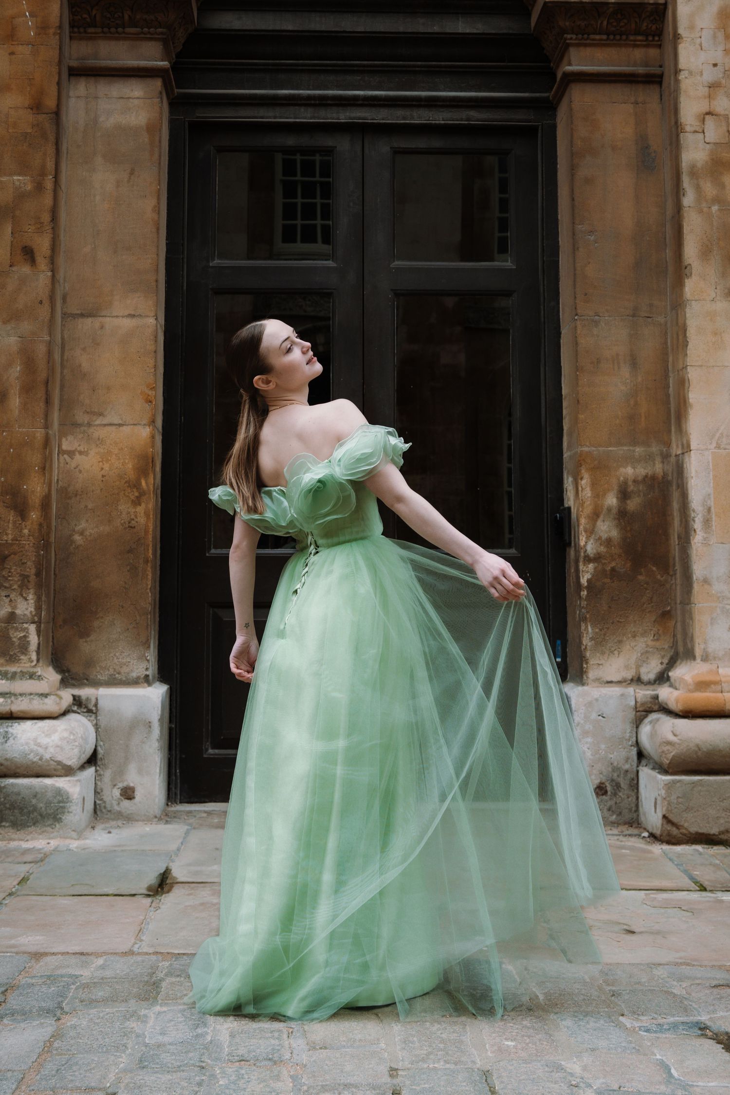Bride in a sage green tulle gown at a stone doorway, wedding portrait by Anya MacLaren Photography