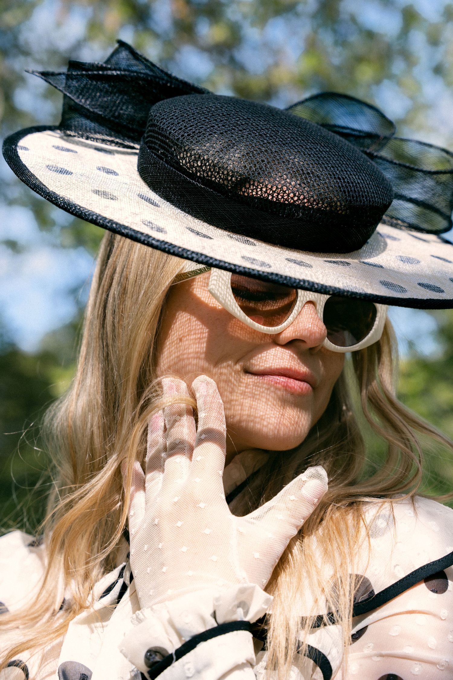 Close-up portrait of a woman in a polka dot hat and sunglasses in dappled sunlight, by Anya MacLaren Photography