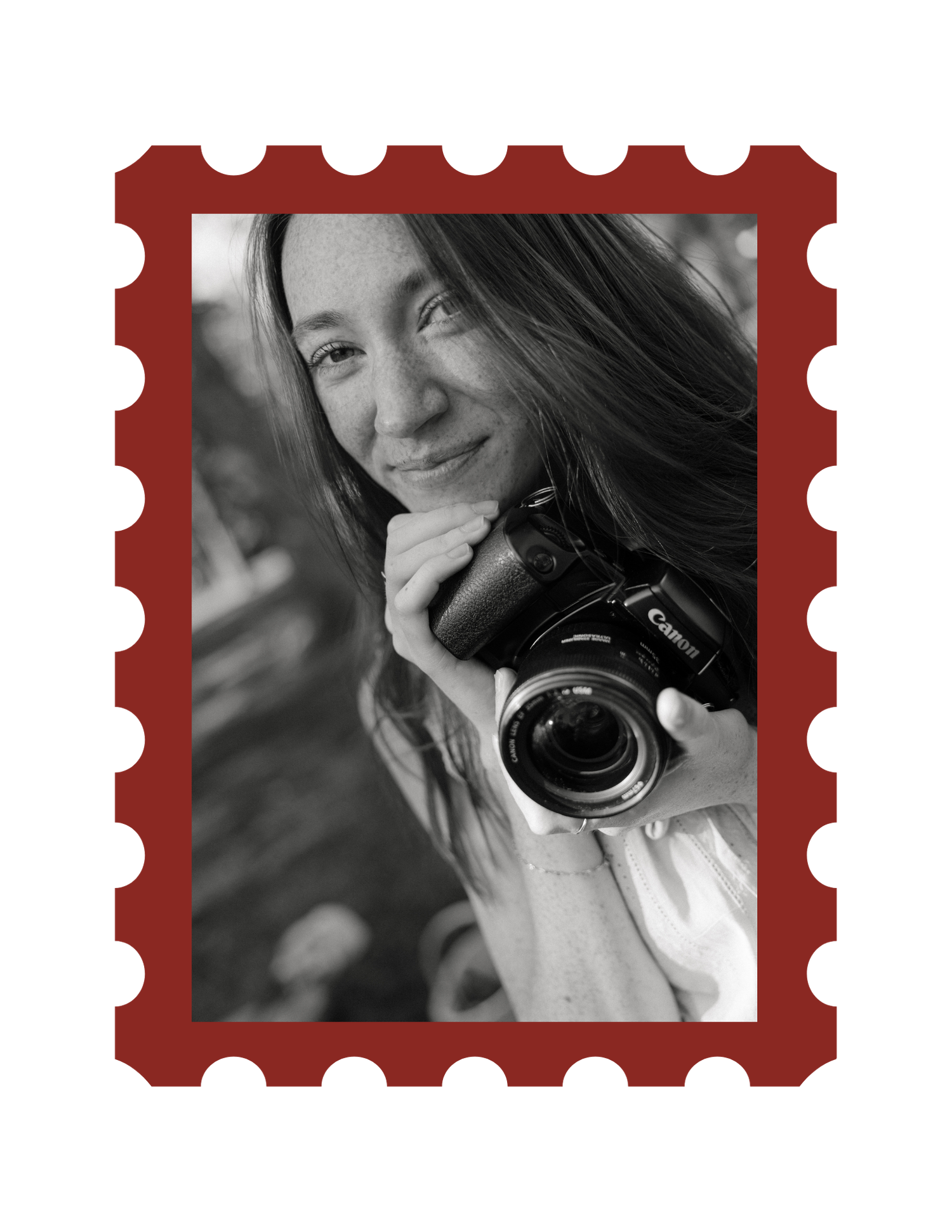 Black and white photo of a smiling woman holding a Canon camera, framed in a red postage stamp border.