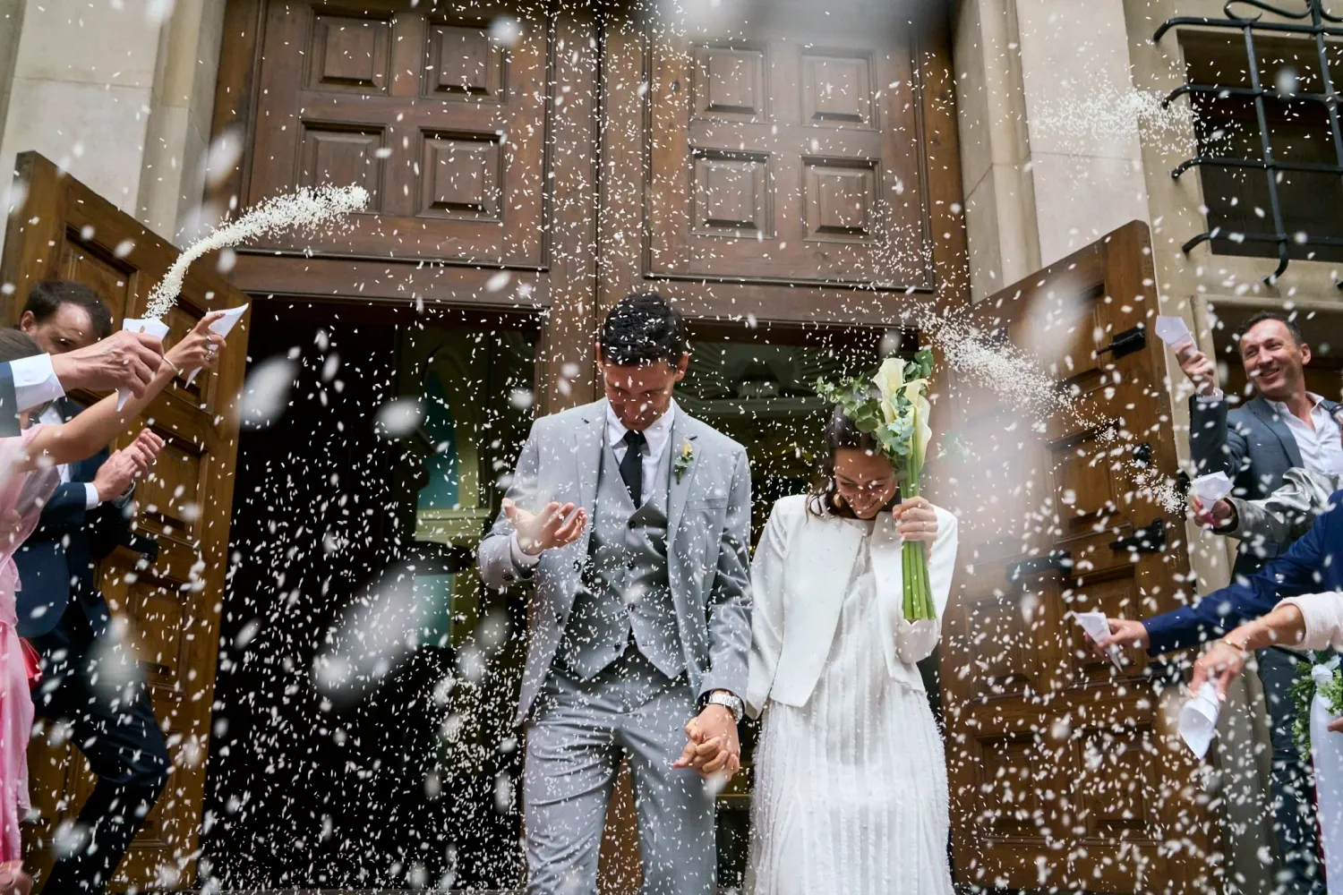 Pareja de novios saliendo De la Iglesia con arroz cayendo sobre ellos