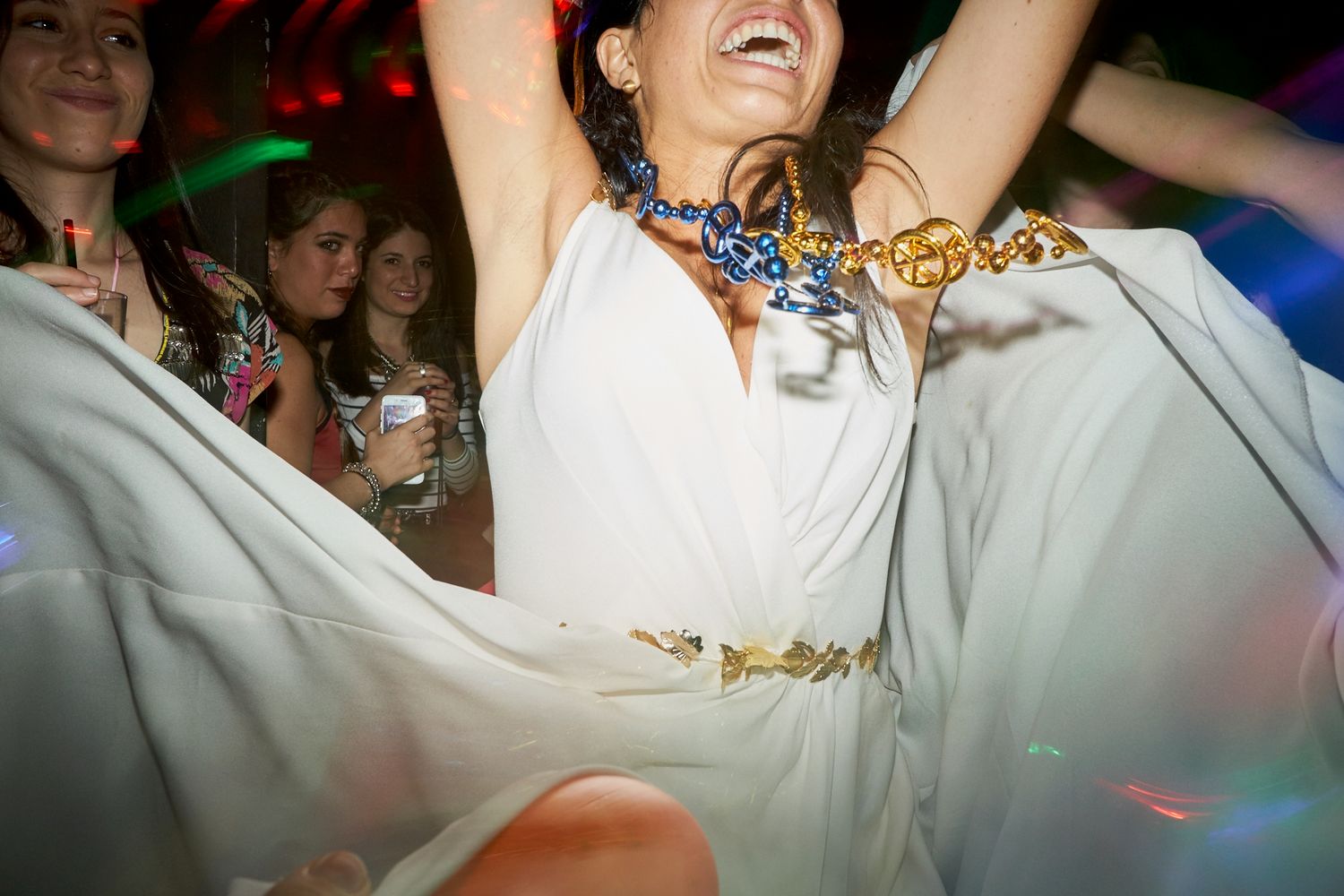 Novia bailando con los brazos en alto, luciendo un collar de eslabones dorados y azules