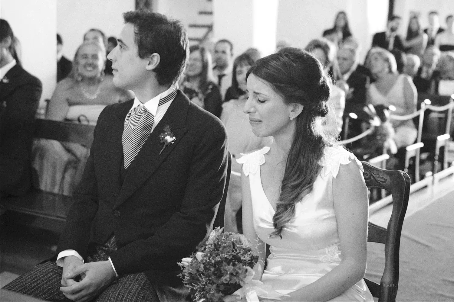Novia emocionada en las sillas del altar, junto a su pareja