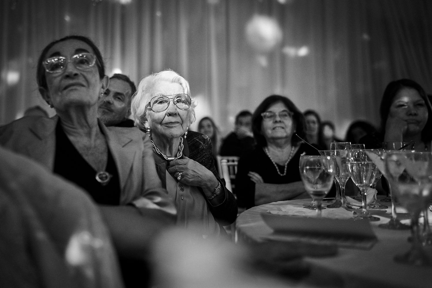 oto en blanco y negro de dos invitadas mayores atentas durante los discursos en la mesa