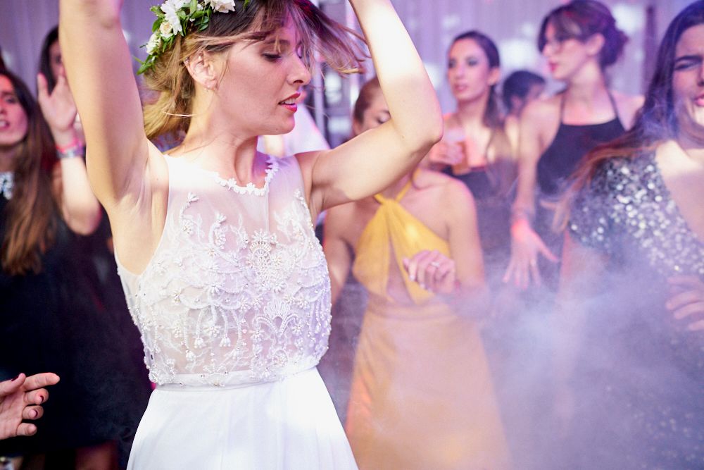 Novia bailando con corona de flores entre humo y luces de colores en la fiesta