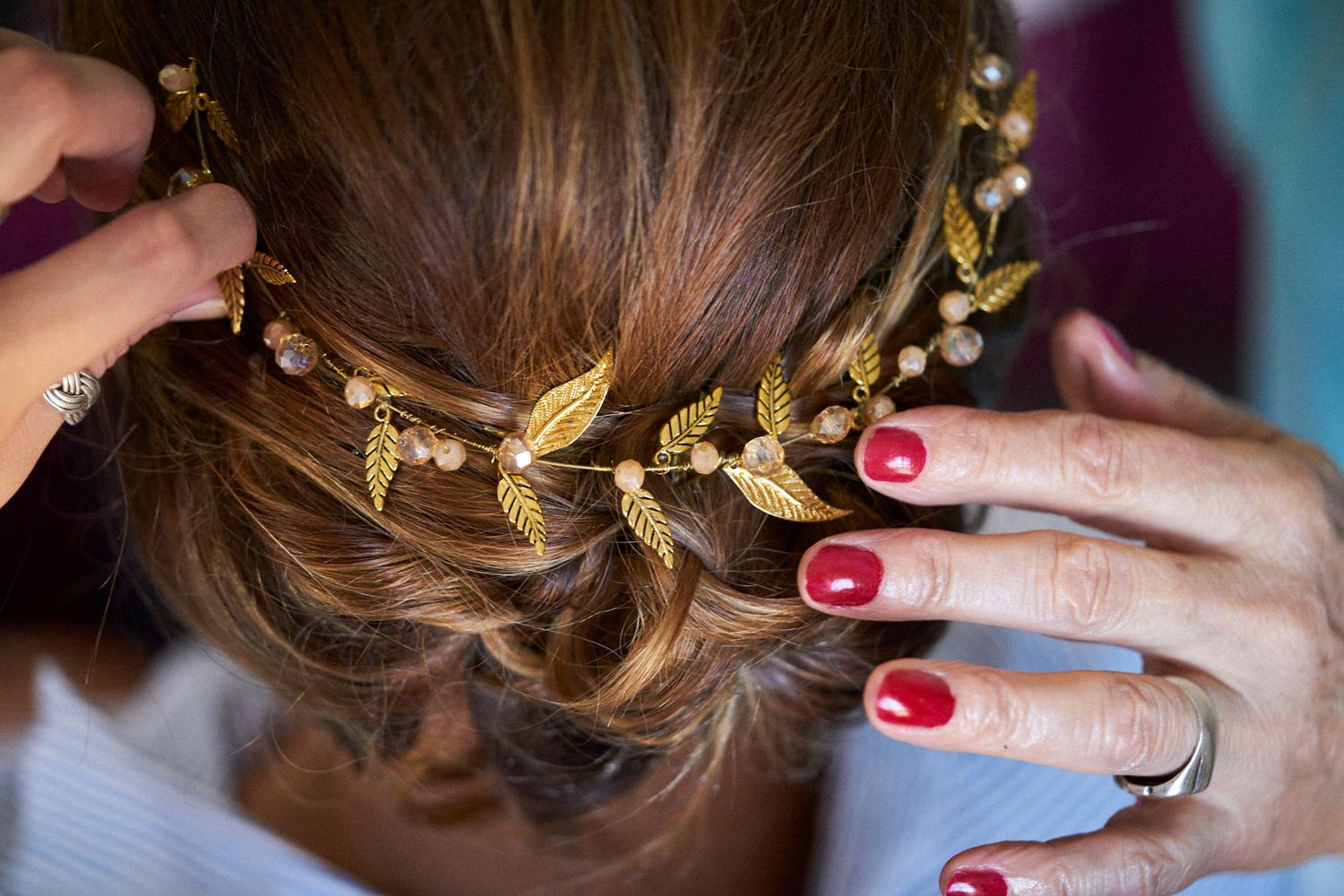 Primer plano de una tiara de hojas doradas y perlas colocada en el cabello de la novia