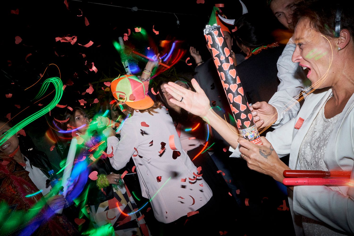 Invitados bailando con bengalas y confeti en forma de corazones durante la fiesta nocturna