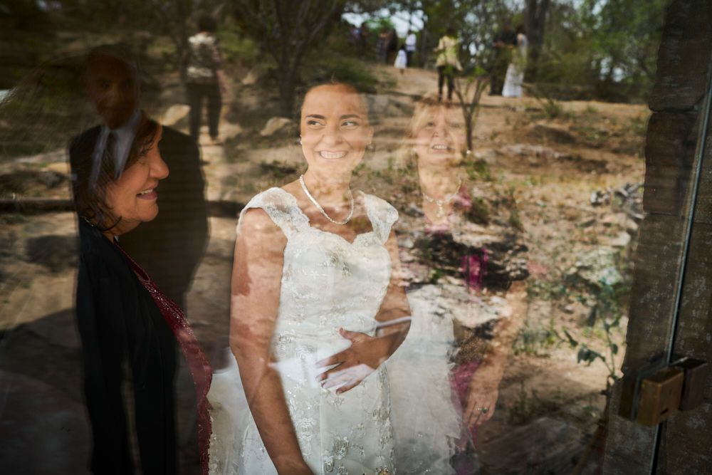 Retrato de la novia sonriente visto a través de un vidrio, con el paisaje reflejado de fondo