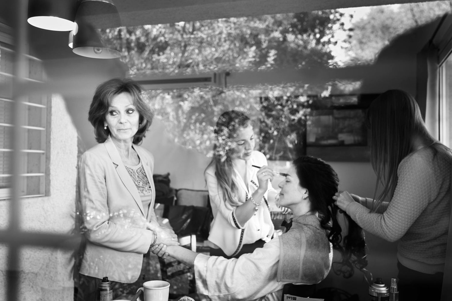 Foto en blanco y negro de la novia siendo maquillada mientras otras mujeres la acompañan durante los preparativos