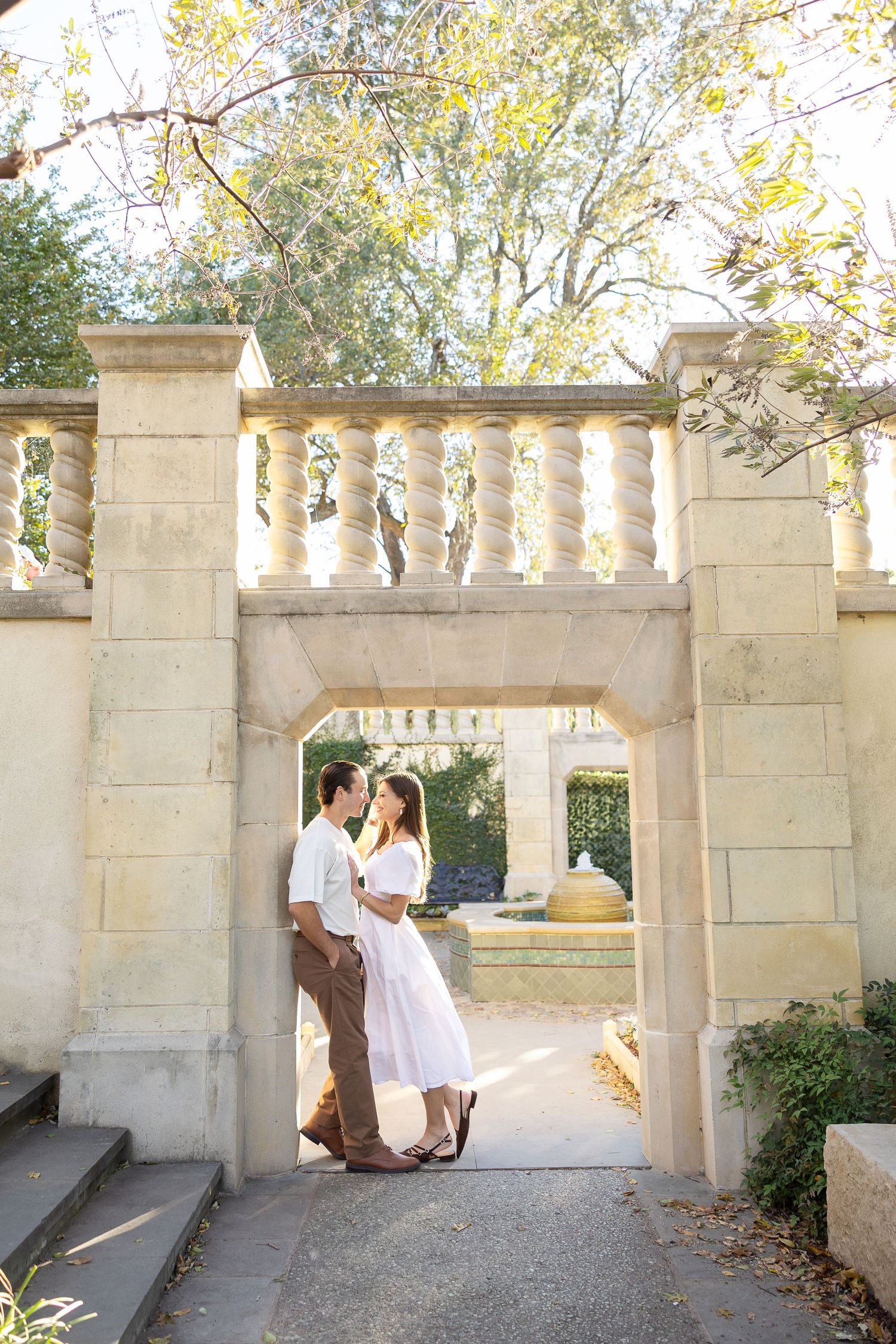 Couple that's getting married in neutrals under a European inspired arch during their engagement photos