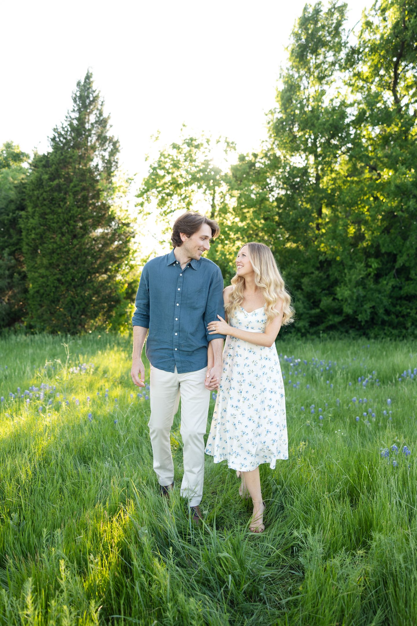 Couple in a grassy field with bluebonnets in white and blue outfits