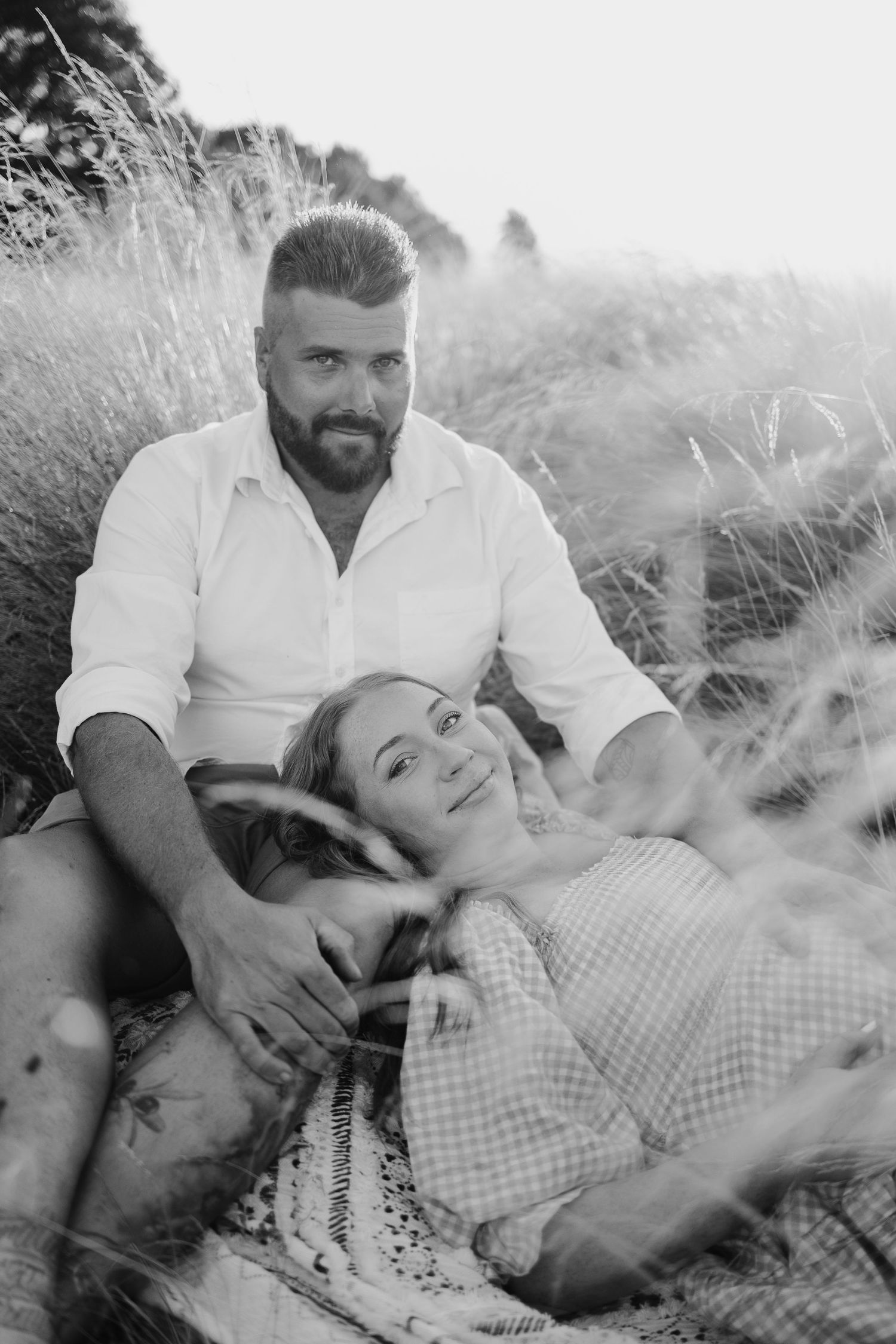 Romantic black and white portrait of couple relaxing in tall grass.