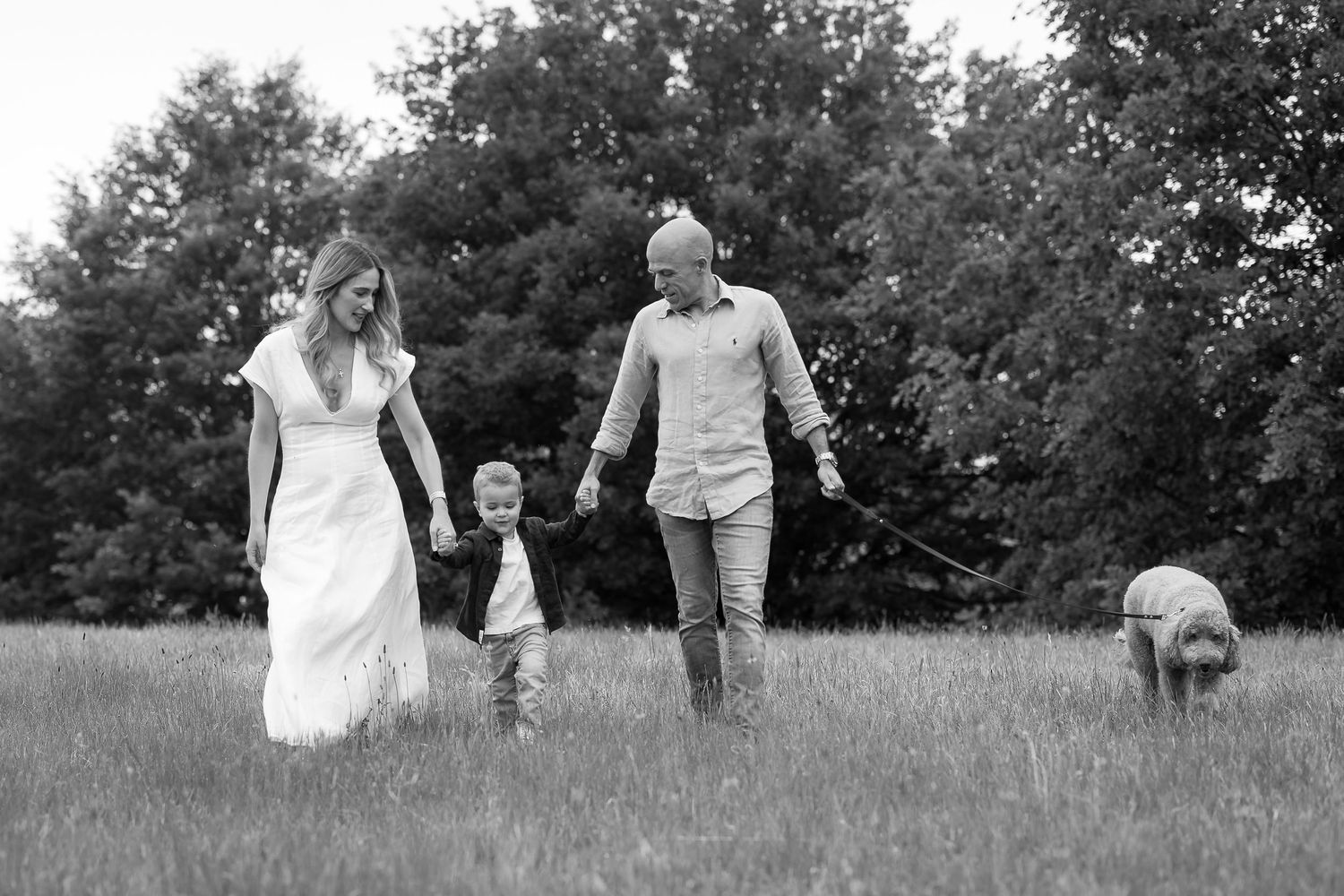 A couple in wedding attire walks hand in hand through a scenic meadow on their special day.