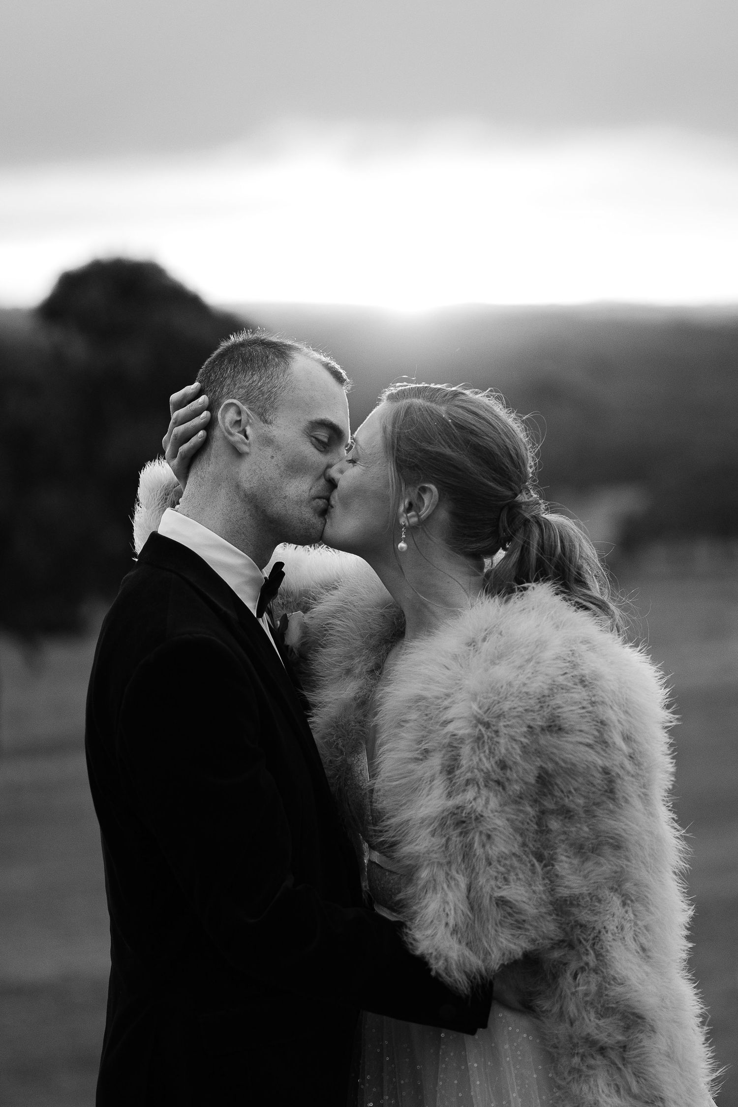 Intimate black and white portrait of newlyweds sharing tender moment outdoors.