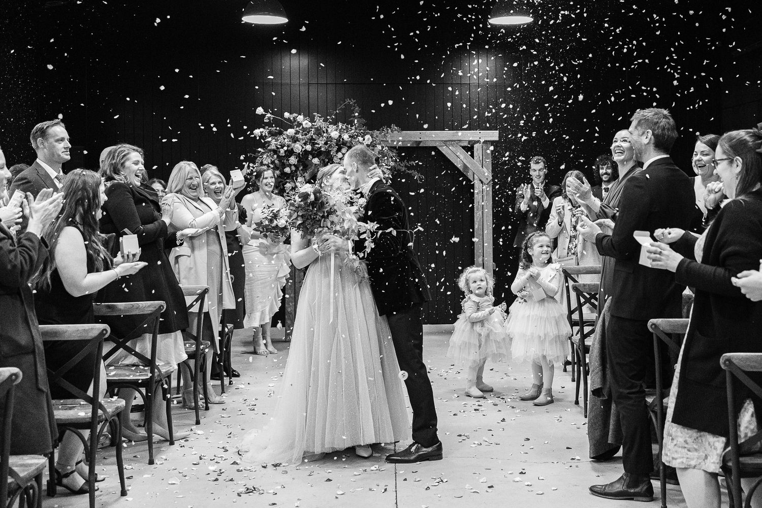Wedding ceremony exit with flower petals being thrown as newlyweds walk down the aisle.