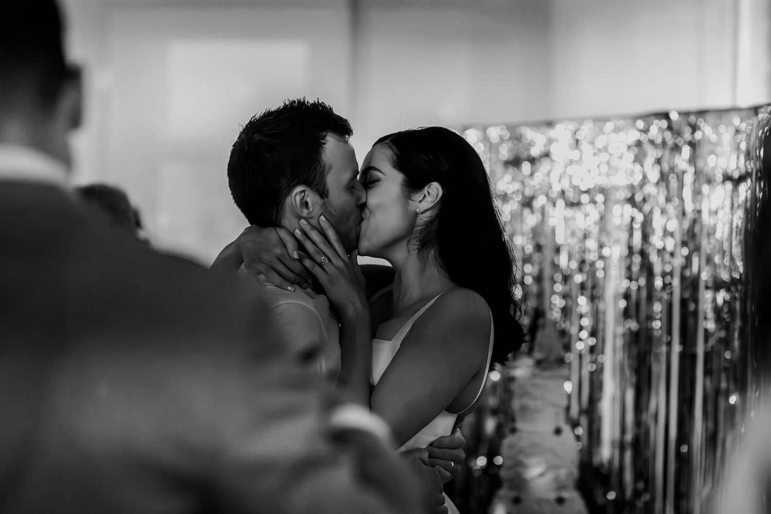 Black and white wedding photo capturing intimate moment between couple with sparkly backdrop.
