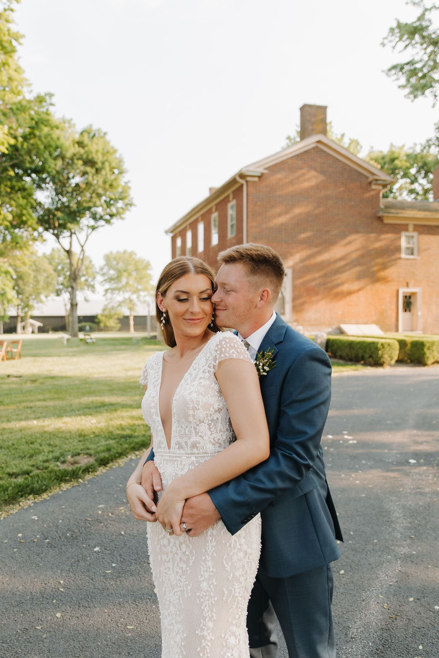 A couple shares an intimate moment outside a brick building on their wedding day in elegant formal attire.