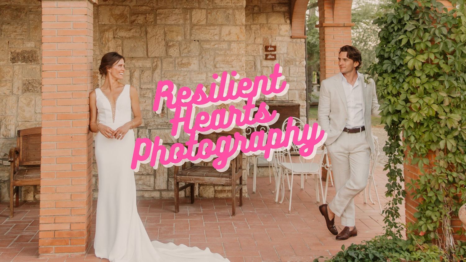 A bride in a white wedding dress poses in front of a rustic stone wall with greenery and pink neon signage.