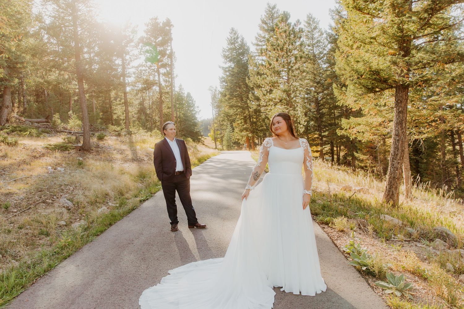 A couple walks hand in hand through a scenic mountain forest path during a golden autumn afternoon.