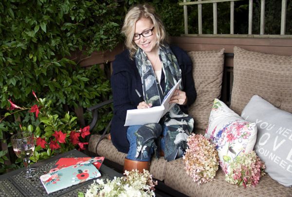 Lifestyle portrait Author Linda Brooks sitting on sofa writing in journal