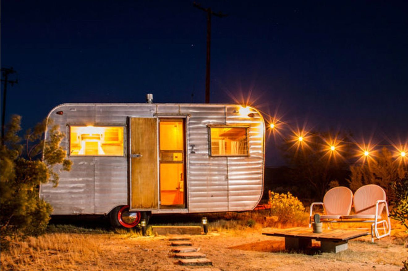 Branding Image Gatos Trail Studio Second Trailer at night with decorative lights leading away from it table and two chairs outside