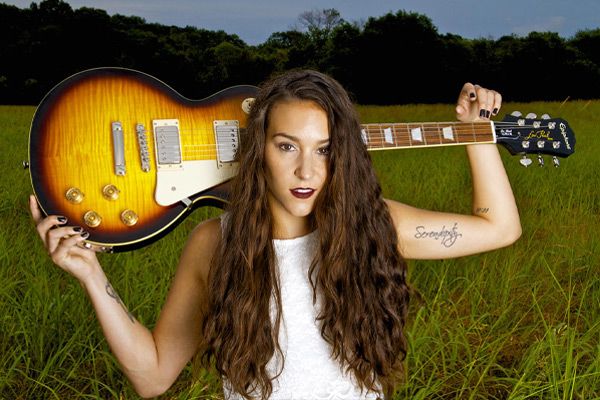 Country music portrait Nashville Tennessee Leanne Pearson standing in tall grass field guitar resting across her shoulders behind her head