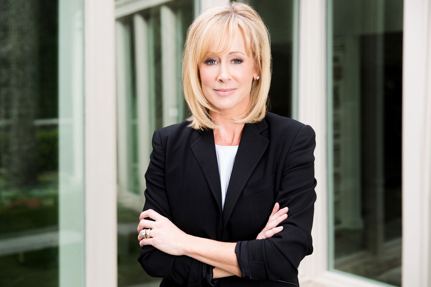 Executive Portrait Andra Liemandt arms crossed in front of green glass windows