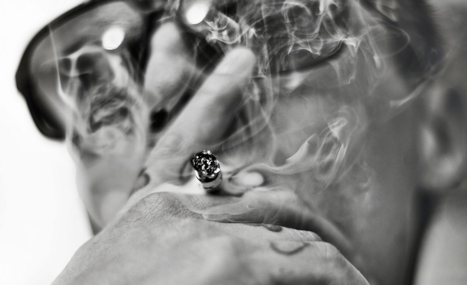 Musician Portrait Artist G closeup smoking while wearing sunglasses black and white