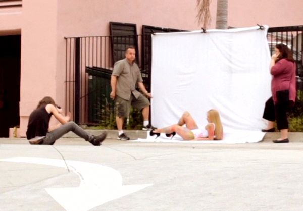 Behind the scenes musician photoshooot Savannah Lynx lying in white bathing suit with painted hand prints against white backdrop