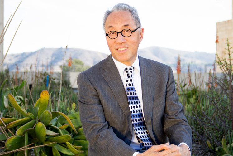 Professional Headshot Dean Michael Woo Pomona hands on knee in front of plants and mountains
