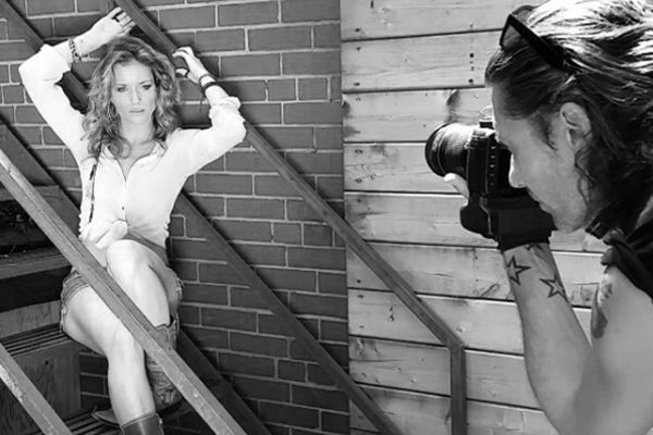 Behind the scenes black and white Mark Maryanovich photographing musician Mandy Bo sitting on metal staircase arms above head