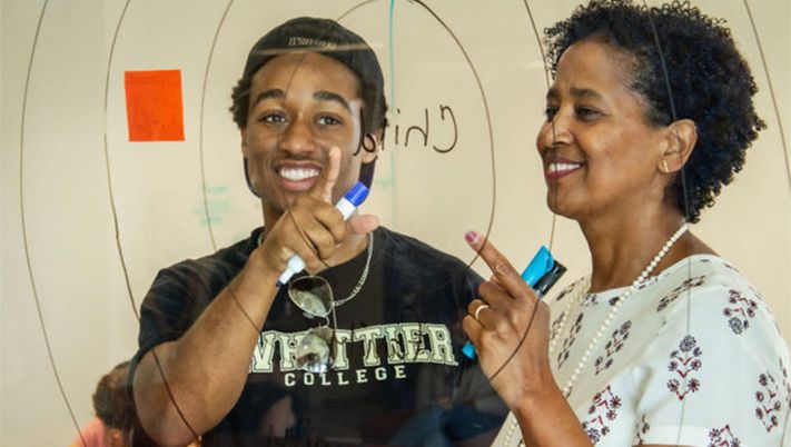 Teacher and Student pointing at diagram on plexiglass with markers in hand